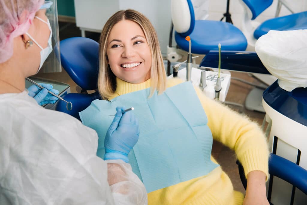 The girl smiles at the dentist and looks at her